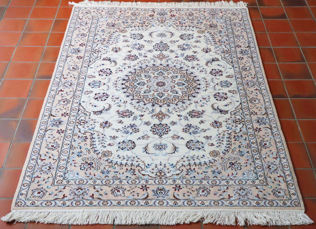 This Nain measures 162 by 109 centimetres.  With a colour palette of cream/ivory background with different shades of blue in the design and tiny touches of a deep burgundy red as an accent colour.   The decoration consists of a complex floral pattern  around a central medallion, the centre of which is a beautiful, delicate flower. This rug has almost a mushroom pink border.