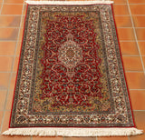 They have used a brilliant bright red for the background shade and cream for the main border with an inner border of gold. The shape of the rug gives the central medallion more of an elongated shape.  Throughout the decoration is of fluid lines depicting flora and fauna.  The colours used to bring out these details are greens, blues and terracotta. 
