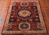 This Choeb-Mamluk rug measures 154 by 100 centimetres. A lovely rug with a brick red background and light coloured border. The central medallion has a deep blue outer border with the centre being a sandy gold colour. They have also used a denim blue and a light blue for some of the detail. The decoration is a stylised floral collection both within the main area of the rug and the border.